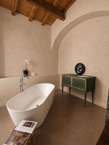 a bathroom with a large white tub and a table at Albergo Diffuso Ginevra Boutique Rooms - Palazzo Leosini - Residenze D'Epoca in LʼAquila