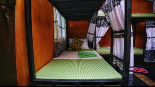 a small room with a green bed in a bus at The Travel Tree Hostel in Sigiriya