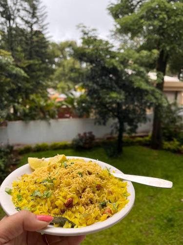 a person holding a plate of food with a fork at Nature Trinity House in Panchgani