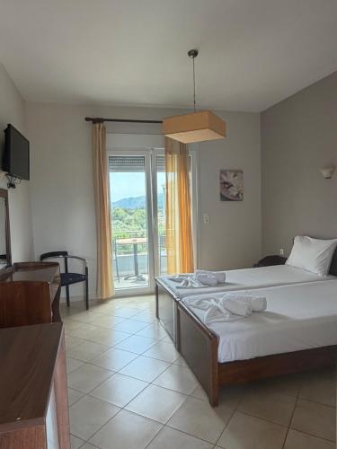 a bedroom with a bed and a large window at Hotel Iliana in Mandrotopos
