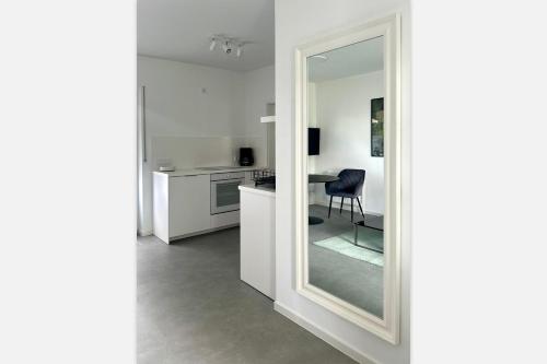 a mirror in a white kitchen with a table at Heide Apartments in Schneverdingen