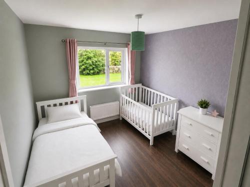 a nursery with two white cribs and a window at Hill house Westport in Castlebar