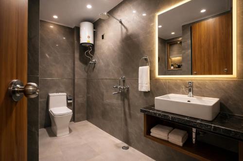 a bathroom with a sink and a toilet and a mirror at Hotel Airport Elite Suit Near Delhi Airport in New Delhi