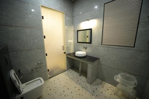 a bathroom with a sink and a toilet and a mirror at Hotel Vantara in Karnāl