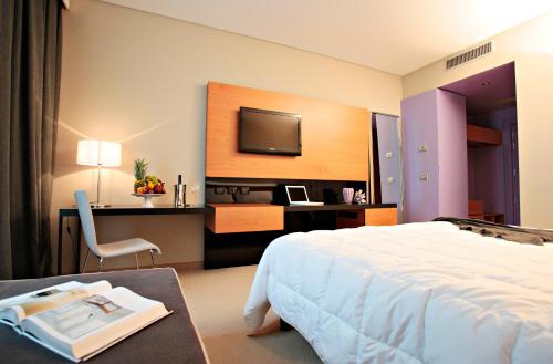 una camera d'albergo con letto e scrivania con TV di Cosmopolitan Hotel a Civitanova Marche
