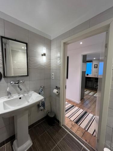 a bathroom with a sink and a mirror and a hallway at Senja Aurora Lodge in Senja