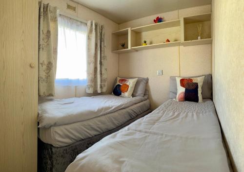 two beds in a small room with a window at Klara Happy Days in Trusthorpe