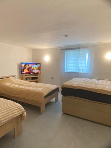 a bedroom with two beds and a tv in it at L&L A66 Ferienwohnung in Gründau