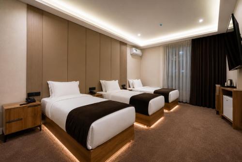 a hotel room with two beds and a television at Carlton Hotel Tashkent in Tashkent