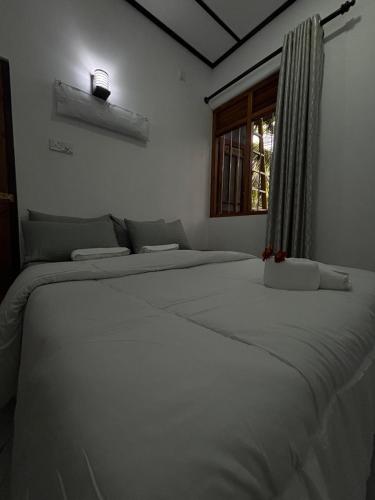 a large white bed in a bedroom with a window at Casa Bella Home in Ja-Ela