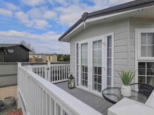 a white deck with a table and a balcony at Sunset Lodge in Warkworth