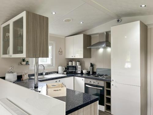 a kitchen with white cabinets and a black counter top at Sunset Lodge in Warkworth