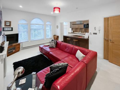 a red leather couch in a living room with a kitchen at Rooftops No83 in St. Leonards
