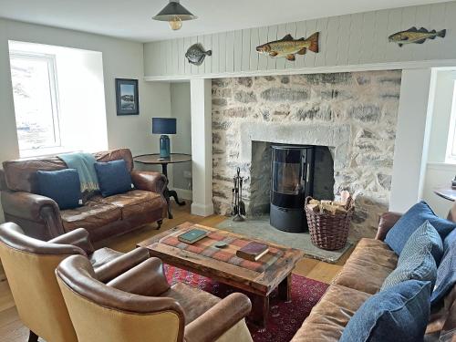a living room with couches and a stone fireplace at The Fish House in Rispond