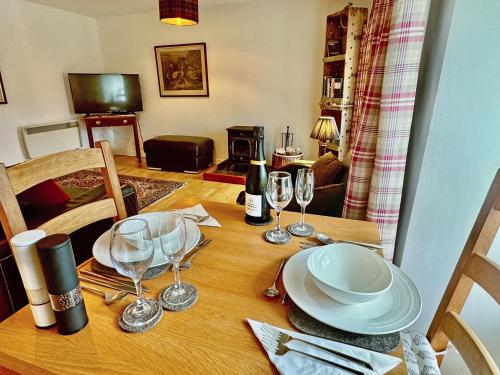 a wooden table with plates and wine glasses on it at The Cottage in Rispond