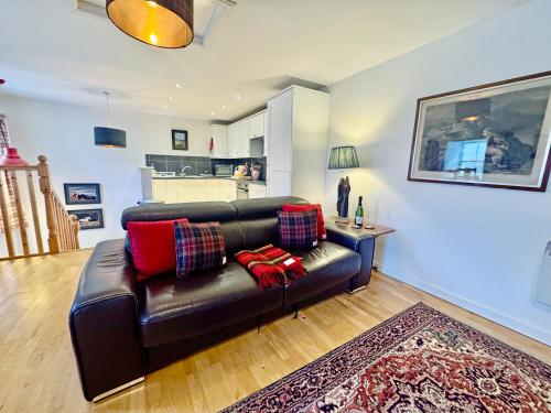 a living room with a black leather couch and a table at The Cottage in Rispond