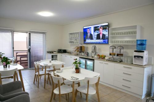 a kitchen with two tables and a tv on the wall at Nesuto Geraldton in Geraldton