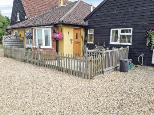 a house with a wooden fence in front of it at Reed Lodge in Littleport