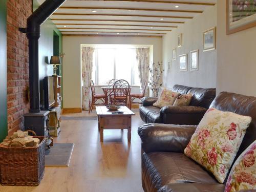 a living room with a leather couch and a fireplace at Reed Lodge in Littleport