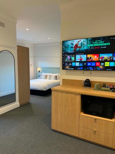 a hotel room with a bed and a large flat screen tv at Tourist Hotel Queanbeyan in Queanbeyan