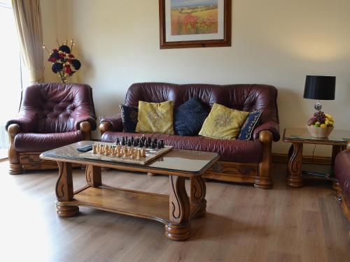 a living room with leather couches and a chessboard at Sedge Lodge in Littleport