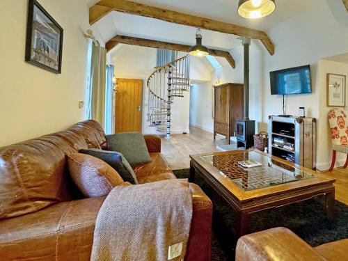 a living room with a leather couch and a coffee table at The Byre in Rispond