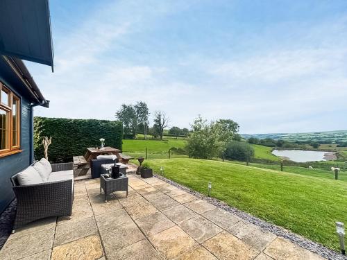 a patio with chairs and a table and a field at Poundgate Lodge in Knighton