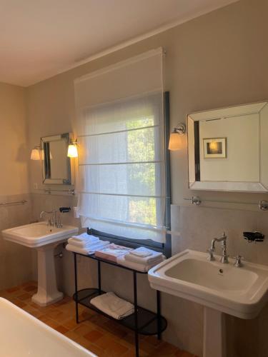 a bathroom with two sinks and two mirrors and a window at La Villa Saint-Antoine in Violès