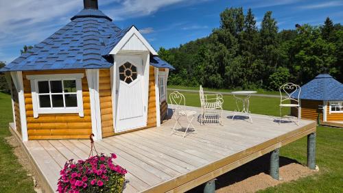 a cabin with a deck with chairs and a table at Antsu Puhkeala Matkamaja in Nüpli