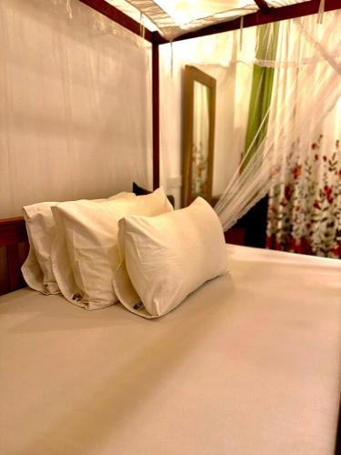 a bed with white pillows on top of it at villa Senoa in Ahangama