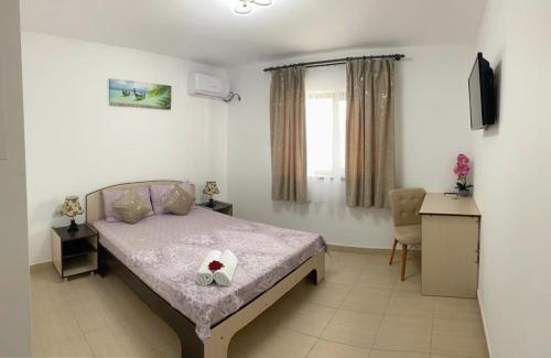 a bedroom with a bed and a desk and a window at Vila Bya in 2 Mai