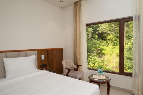 a bedroom with a bed and a window and a chair at The Aralia in Dehradun