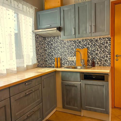 a kitchen with gray cabinets and a sink at Yasmin Apartment in Pärnu
