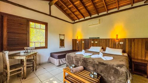 a bedroom with a bed and a desk in it at Pousada Portal do Cacau-Petfriendly in Camburi
