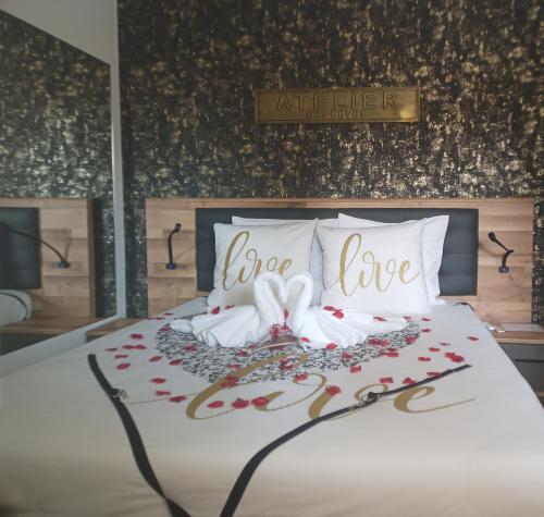 a bed with white pillows and a sign that says open love at Love Room Emoi de toi in Sigean