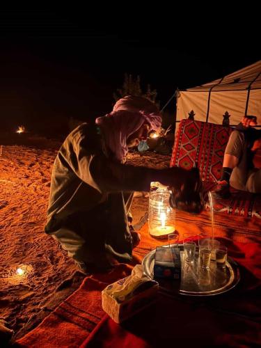 a person sitting on the beach in front of a tent at Camp la mer de sable in Mhamid