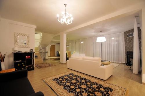 a living room with a white couch and a chandelier at Villa Lina Kerkira in Gouvia