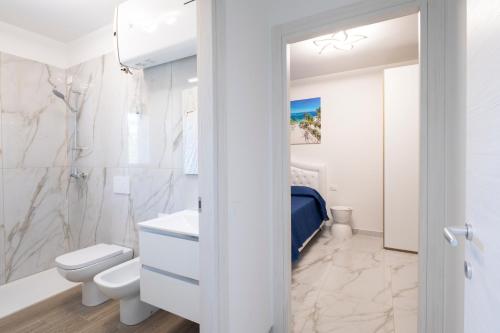 a white bathroom with a toilet and a sink at Don Cesar Palace in Bibione