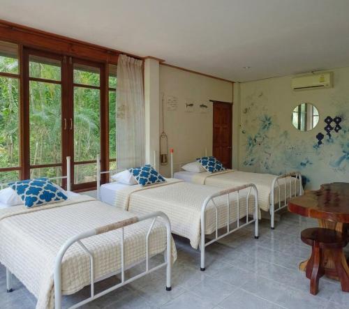 a group of four beds in a room with windows at SN Garden in Ban Bo Hin