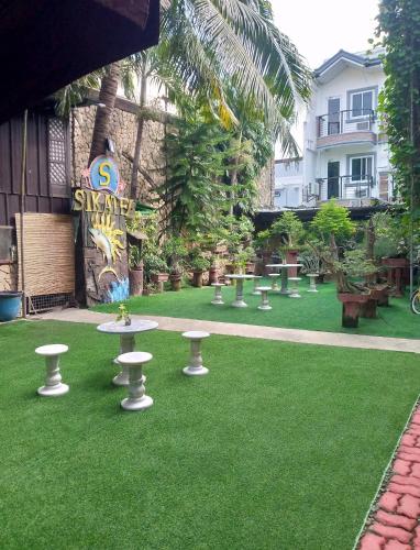 a green lawn with tables and chairs on it at Sikatel Hotel in Batac