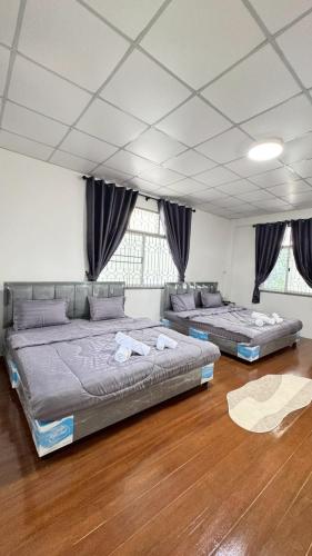two beds in a room with wooden floors and windows at Triple T House in Hat Yai