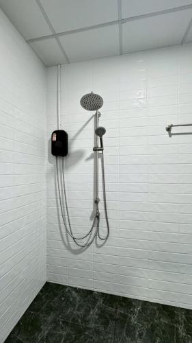 a shower in a white wall with a shower head at Triple T House in Hat Yai