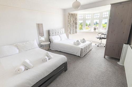 a white bedroom with two beds and a desk at Gateway to Gower in Dunvant