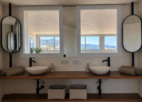 a bathroom with two sinks and two mirrors at Pensión Sevillano in Nerja