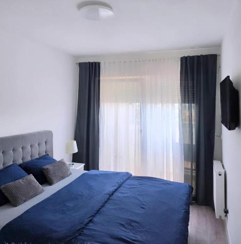 a bedroom with a blue bed and a window at XENA Centar Gradiška in Bosanska Gradiška