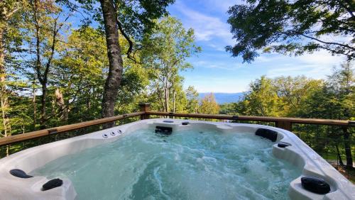 a hot tub on a deck with trees in the background at Modern Chalet Hot Tub Game Loft 1 Mi to Skiing in Beech Mountain