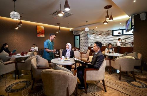 a group of people sitting at tables in a restaurant at Purest Hotel Sungai Petani in Sungai Petani