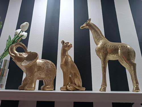 Drei goldene Skulpturen von Giraffen und einem Elefanten auf einem Regal in der Unterkunft Petruccio in Zrenjanin