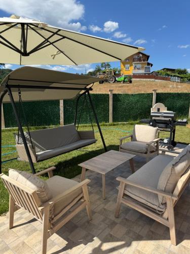 a patio with a swing and chairs and a grill at Къща за гости Пегас in Velingrad
