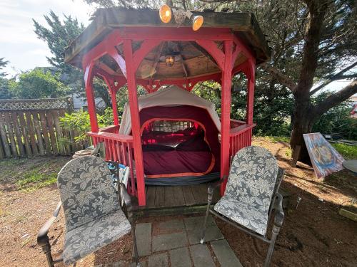 a red gazebo with two chairs and a bed at DiscoCat Studios in Ocracoke